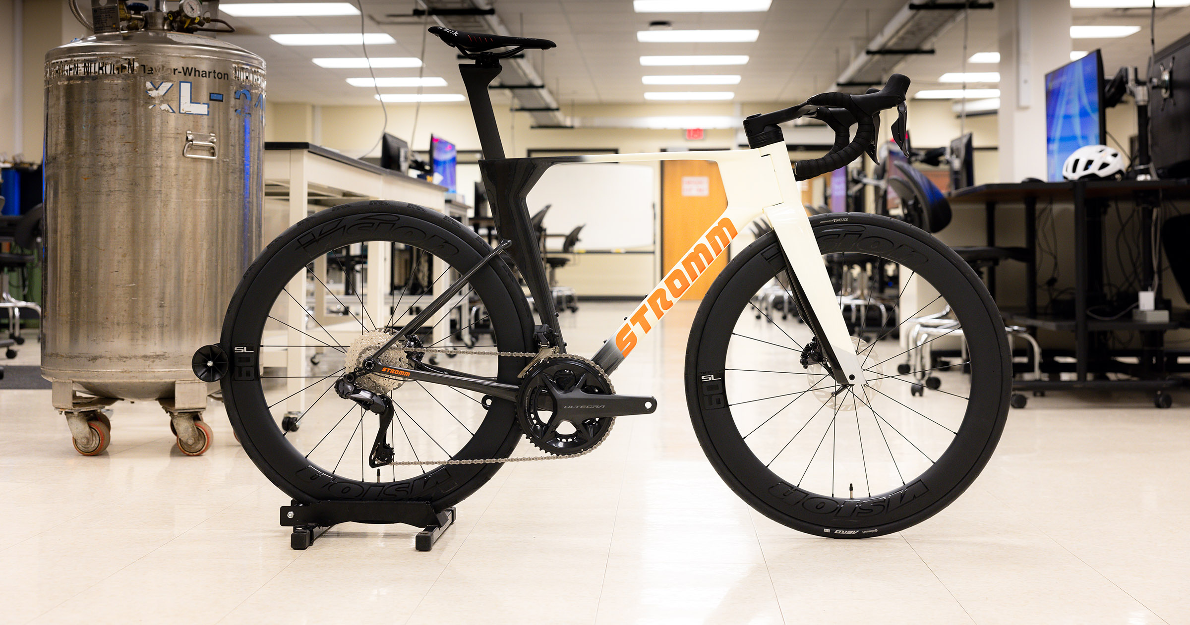 A black, white, and orange Stromm road bike in a laboratory.